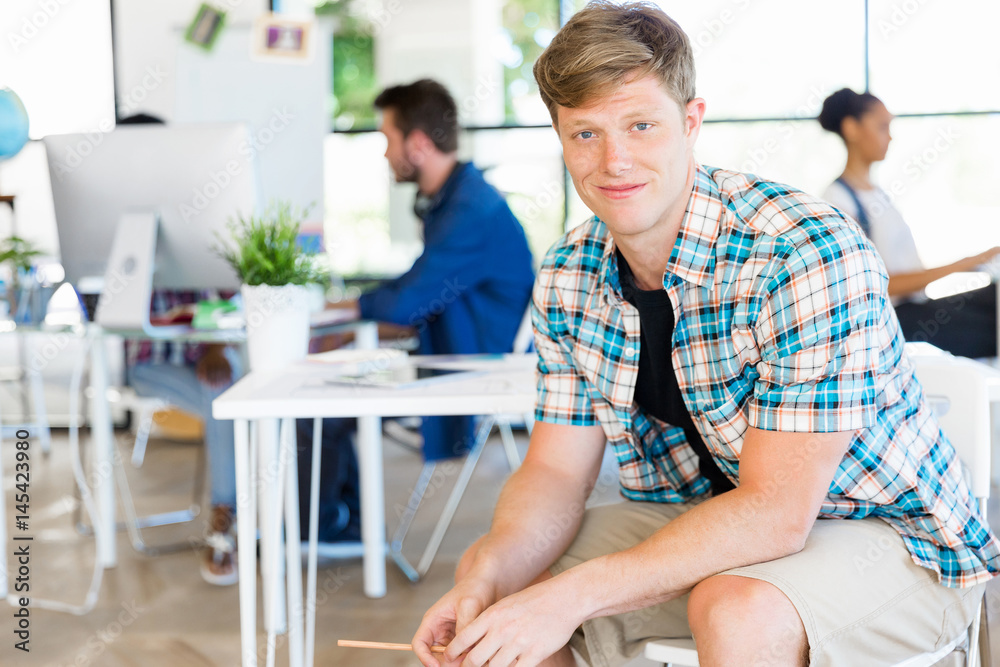 Young man sitting and looking at camera in office Young man sitting and looking at camera in office