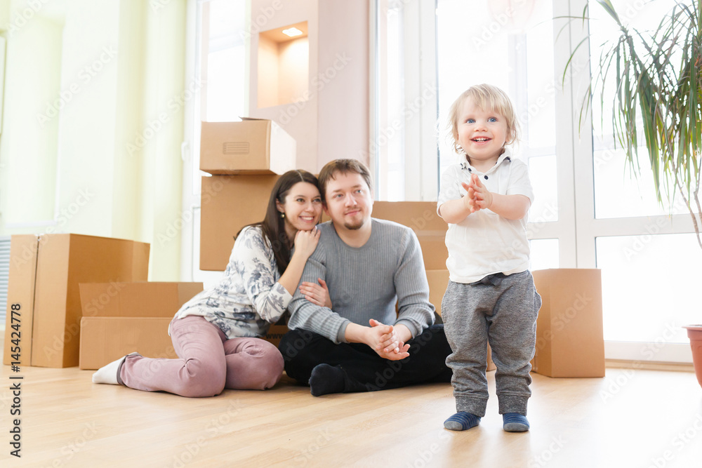 Happy young family with unpacking boxes at new home on moving day Happy young family with unpacking boxes at new home on moving day