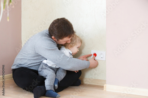Father takes care of the safety of the child. Electrical security for safety home of ac power outlet for babies