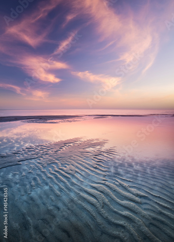Sand on the seashore during sunset. Beautiful natural seascape in the summer time