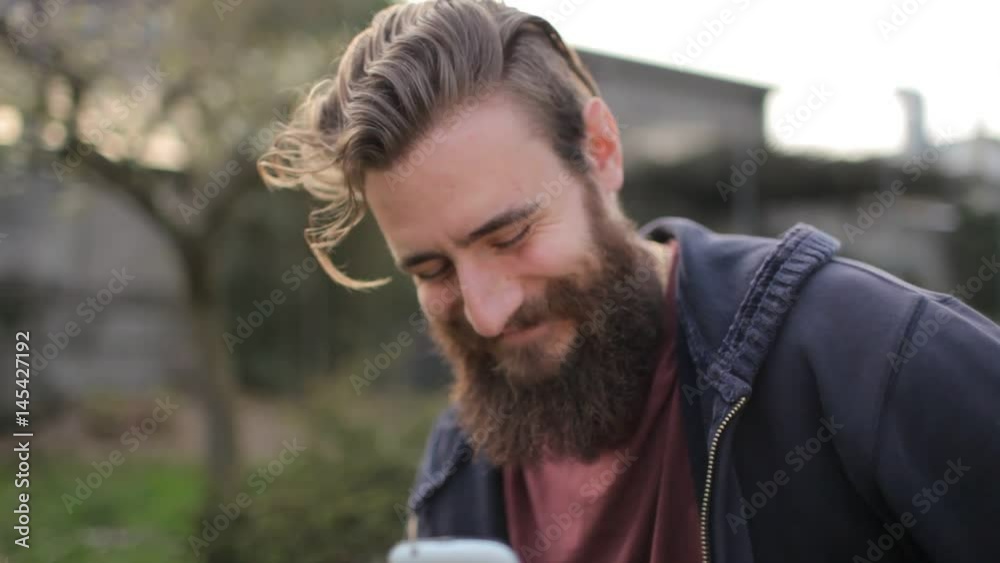 Young bearded caucasian man chatting on the phone, smiling Young bearded caucasian man chatting on the phone, smiling