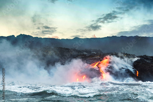 Molten lava flowing into the Pacific Ocean on Big Island of Hawaii at sunrise