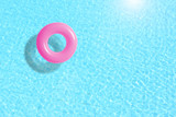 pink swimming pool ring float in blue water. concept color summer.