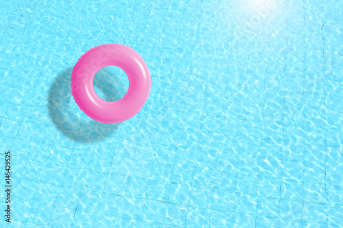pink swimming pool ring float in blue water. concept color summer.