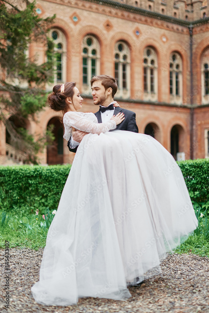 Fototapeta premium Groom carrying bride in park