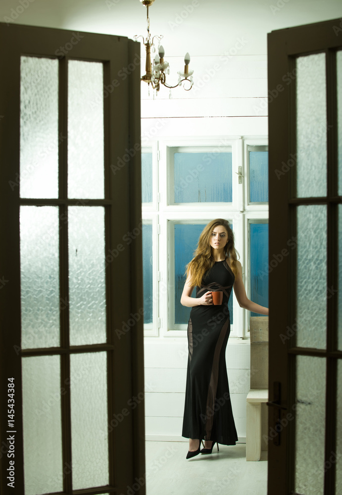 Pretty girl in black dress through open doors