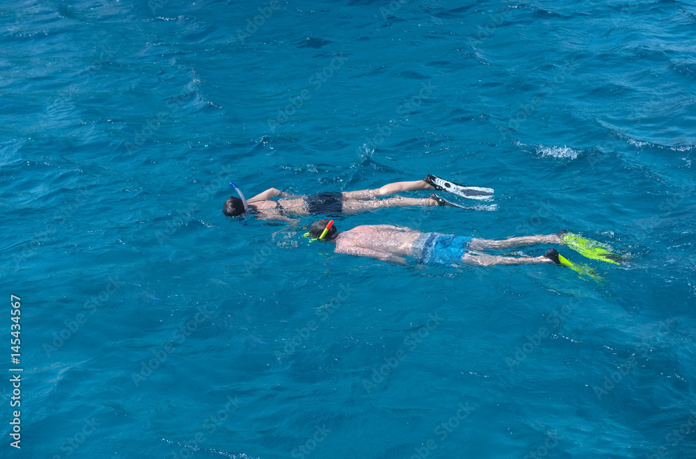 Young couple of swimmers snorkeling in sea