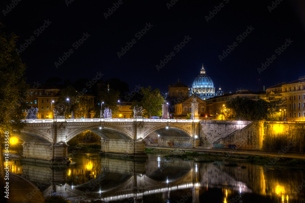 Die Brücke Ponte Vittorio Emanuele II mit dem Petersdom im Hintergrund in Rom bei Nacht.

The bridge Ponte Vittorio Emanuele II with St. Peter's Basilica in the background in Rome at night.