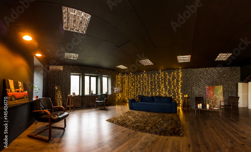 Dark blue sofa, leather armchairs, mirror in stylish loft interior. Photo studio interior