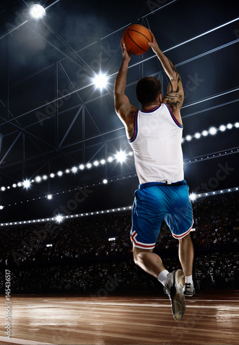 one basketball player jumping with ball on stadium in lights