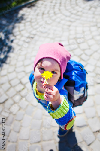 The boy with the backpack shows a dandelion flower.