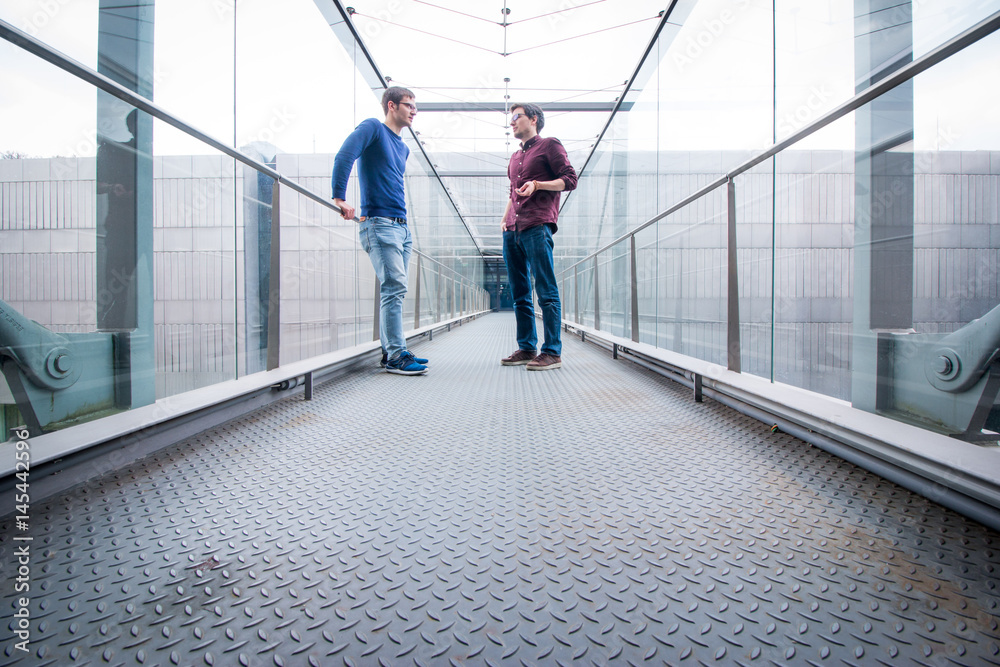 Mitarbeiter unterhalten sich im Gang, modernes Gebäude Mitarbeiter unterhalten sich im Gang, modernes Gebäude