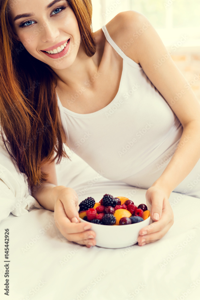 Smiling woman with plate of fruits, indoors
