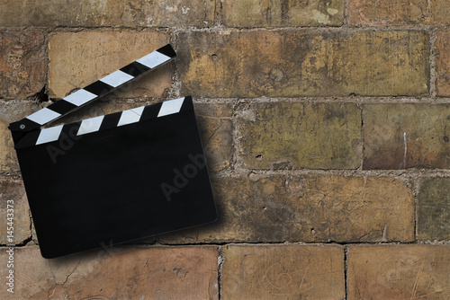 Ciak posizionato sopra a mura composto da vecchi mattoni. Immagine astratta applicabile per industria del cinema, produzione di filmati, inizio attività, startup, nuove sfide e cambiamenti. 
