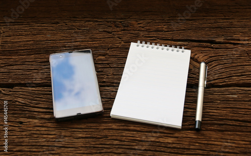 note pad and smartphone on Old Wood Table.