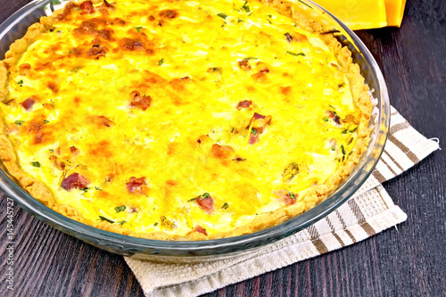 Quiche with pumpkin and bacon in pan on board
