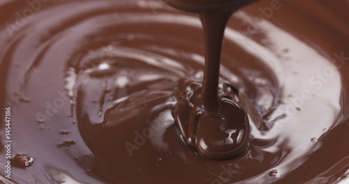 Slow motion of premium dark melted chocolate being poured from spoon in right part of frame  4k photo