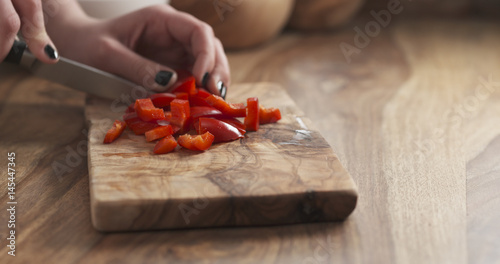 teen girl cuts bell pepper on olive cutting board, 4k photo