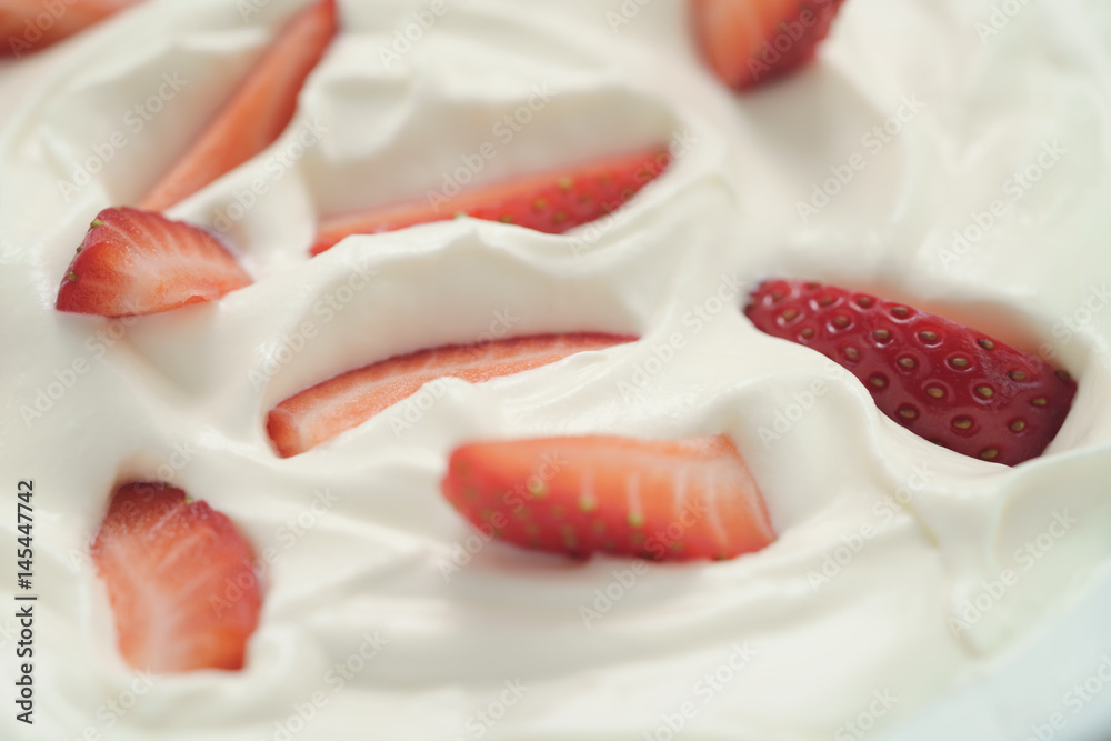 closeup of organic sliced strawberries in whipped cream, food background closeup of organic sliced strawberries in whipped cream, food background