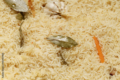 pilaf covered by rice with bay leaves preparing, closeup photo