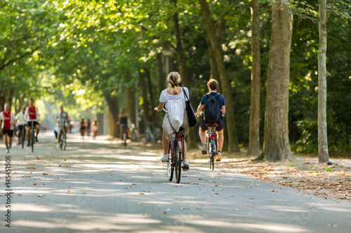 A girl and boy biking in the sunny Amsterdam Vondelpark. The Netherlands.