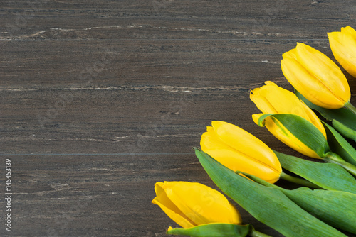 Yellow tulips on grey wooden board. Background  pattern  texture.