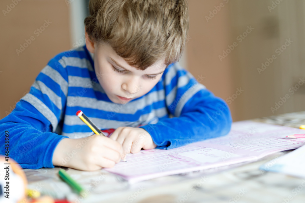 Happy school kid boy at home making homework Happy school kid boy at home making homework