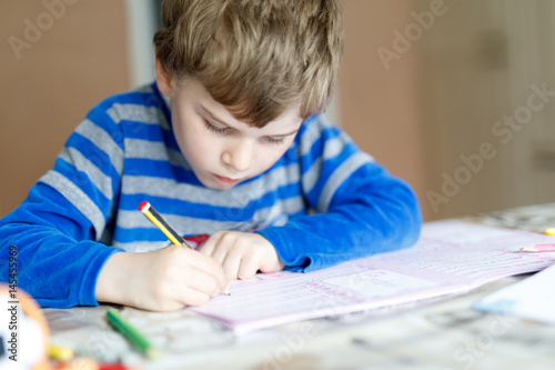 Happy school kid boy at home making homework