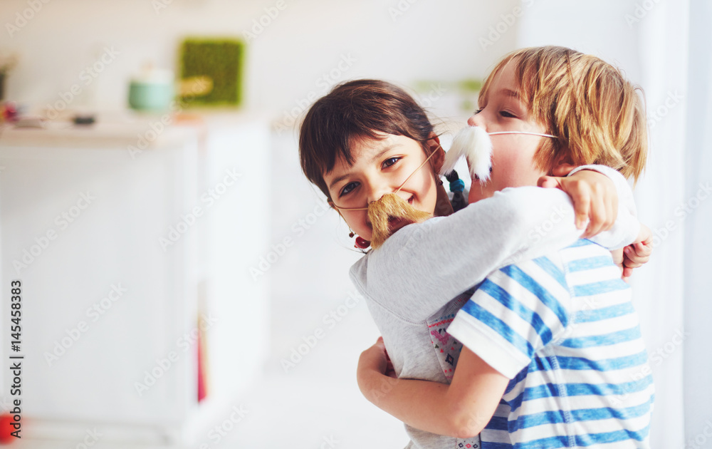 excited kids with mustaches embracing at home