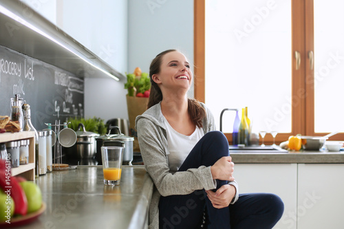 Young woman sitting a table in the kitchen .