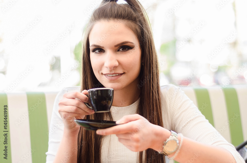 Portrait brightly lit girls in a cafe drinking coffee with a smile Portrait brightly lit girls in a cafe drinking coffee with a smile