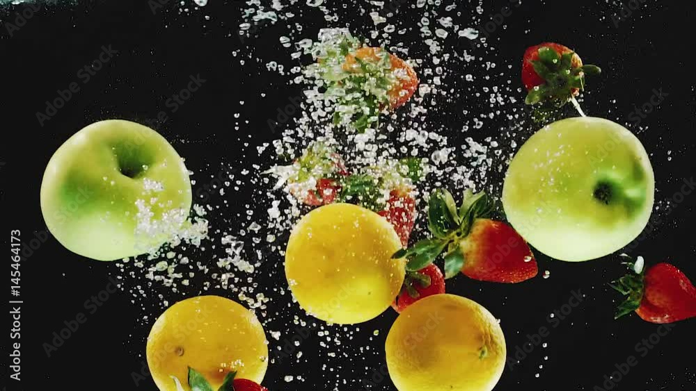 A lot of oranges, apples, strawberries falling into water in slow motion