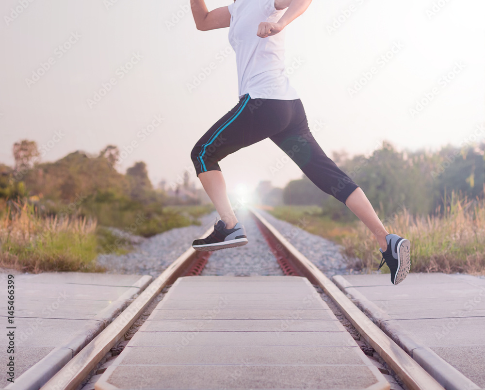 Young woman jumping above the railway during the jogging, Healthy lifestyle and sport concepts.