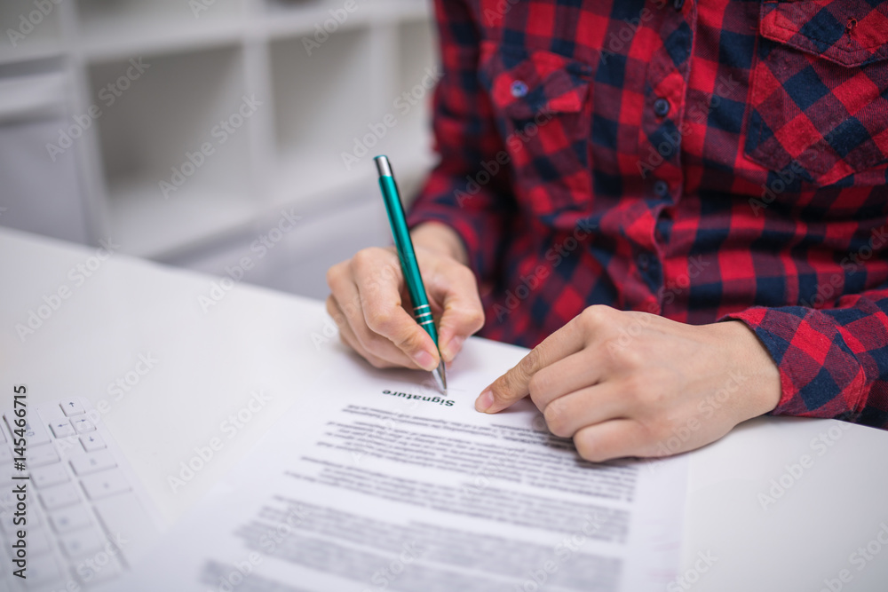 Woman at office desk signing a contract Woman at office desk signing a contract