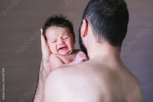Newborn baby and dad. Baby boy crying on his father shoulder. 