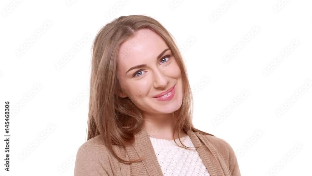 Cute young blue-eyed Caucasian female with light brown hair standing on white background shy coy flirting smiling in slowmotion Cute young blue-eyed Caucasian female with light brown hair standing on white background shy coy flirting smiling in slowmotion