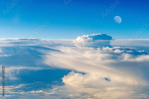 The colorful sky above the clouds with half moon airplane traveling in the summer