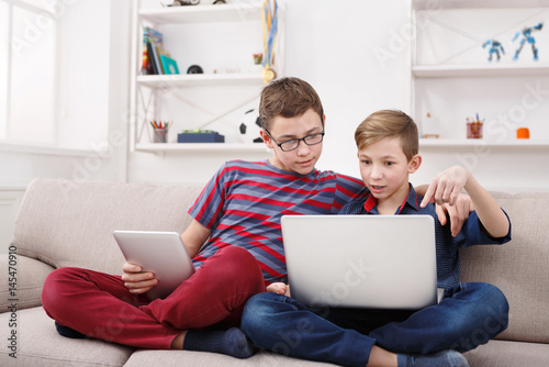 Obraz na płótnie Two teenage boys using tablet on couch at home