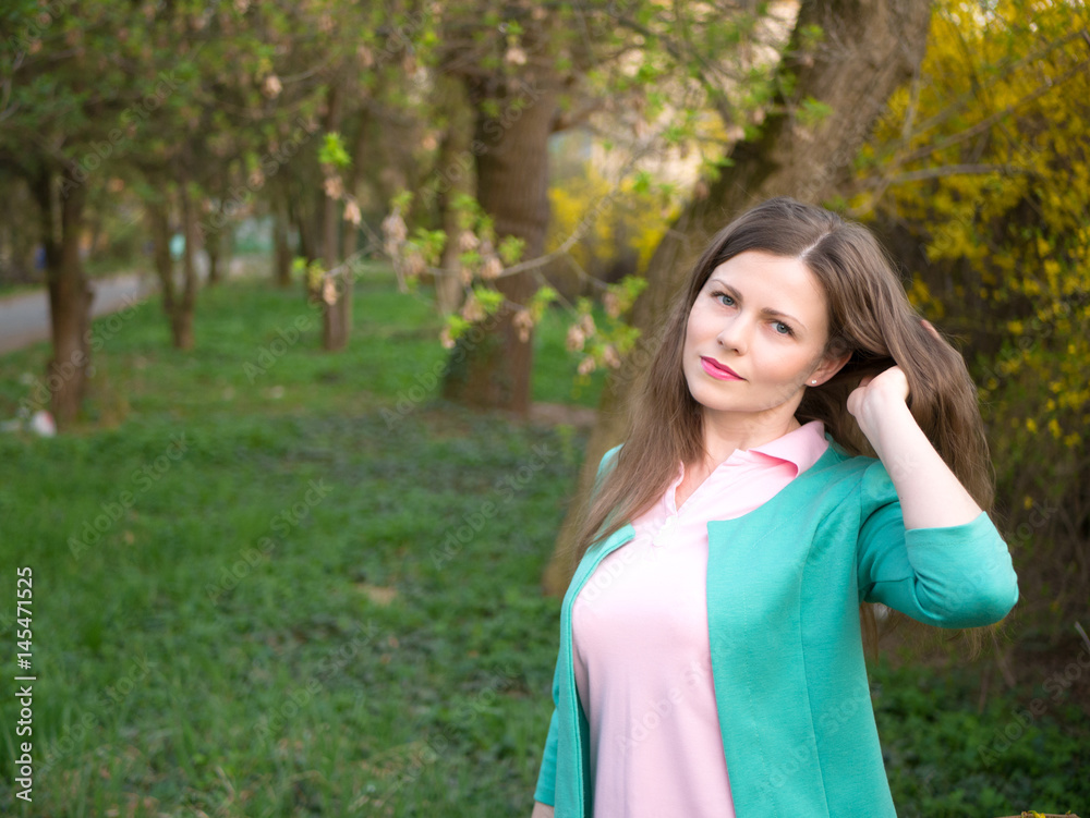 outdoor portrait beautiful girl in green jacket among yellow blossom tree