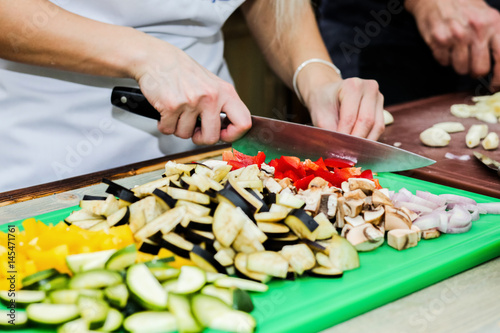 The chef in the kitchen prepares healthy food with vegetables.