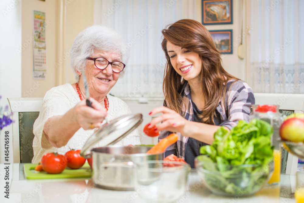 Grandmother and her granddaughter preparing healthy food together in the kitchen. Grandmother and her granddaughter preparing healthy food together in the kitchen.