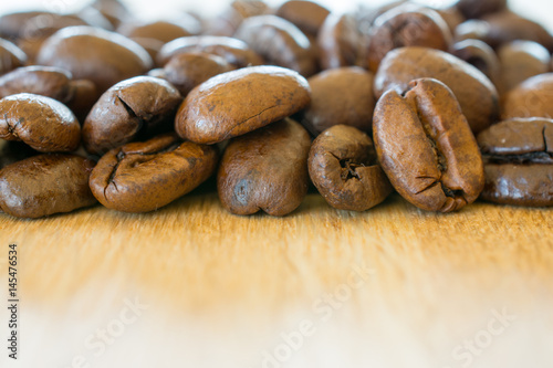 Coffee beans on wooden table closeup.