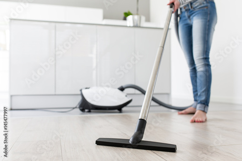 Woman using Vacuum Cleaner in Kitchen