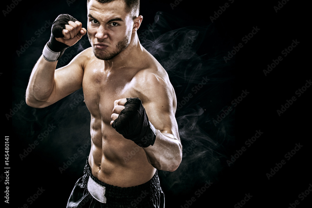 Sportsman muay thai boxer fighting in boxing cage. Isolated on black background with smoke. Copy Space.