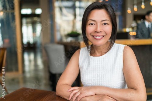 Happy elegant Asian middle-aged businesswoman smiling portrait. Beautiful mature Chinese business woman in fancy restaurant, China.
