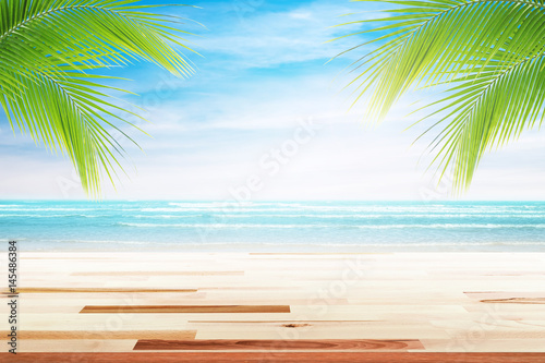 Empty wooden table and palm leafs with party on beach background blurred. Concept Summer  Beach  Sea  Relax  Party.