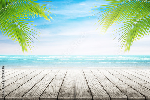 Empty wooden table and palm leafs with party on beach background blurred. Concept Summer, Beach, Sea, Relax, Party.