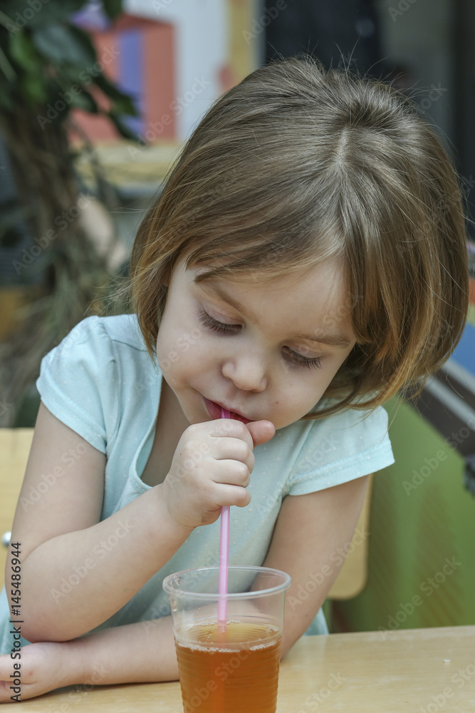A small charming child drinks juice. A child is a girl 4-5 years old. A small charming child drinks juice. A child is a girl 4-5 years old.