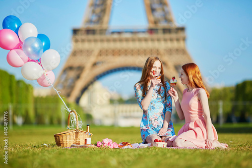 Two young women having picnic near the eiffel tower in Paris, France photo