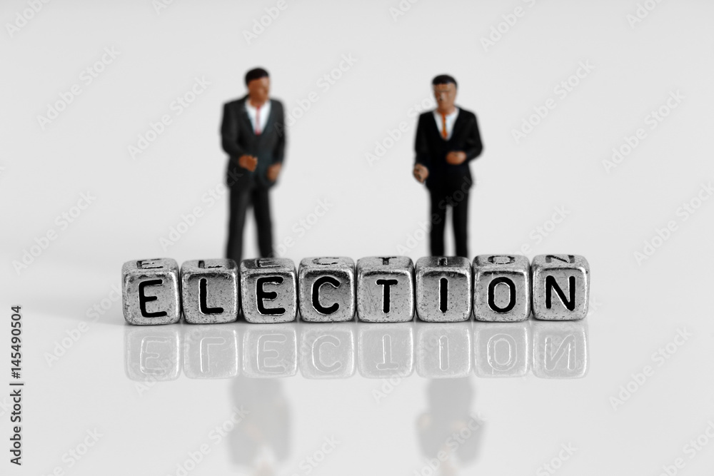 Miniature scale model politicians standing behind the word election on beads Miniature scale model politicians standing behind the word election on beads